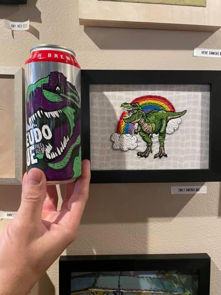 Can of beer in front of a T-Rex painting